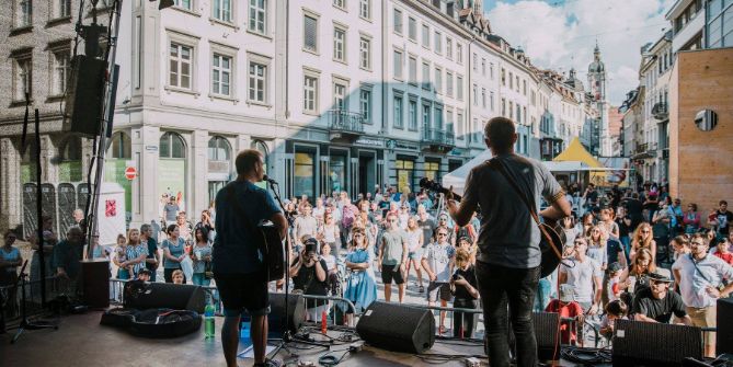 Blick von der Bühne aus auf Konzertbesucher*innen, die auf der Piazza stehen