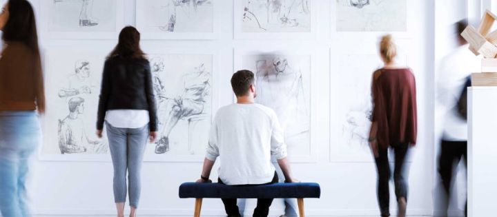 Persone in un museo osservano le opere d’arte alla parete