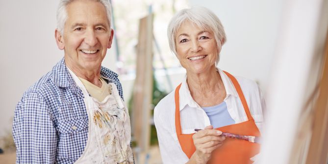 Couple âgé portant un tablier pendant un cours de peinture