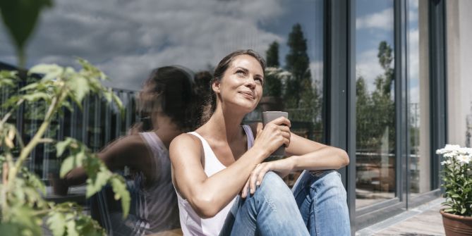 Femme souriant au soleil un café à la main