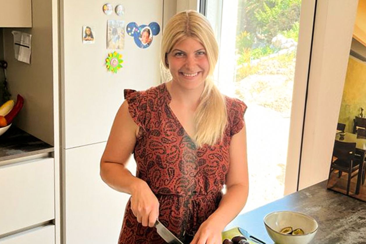 Una donna è in piedi in cucina e taglia la frutta.
